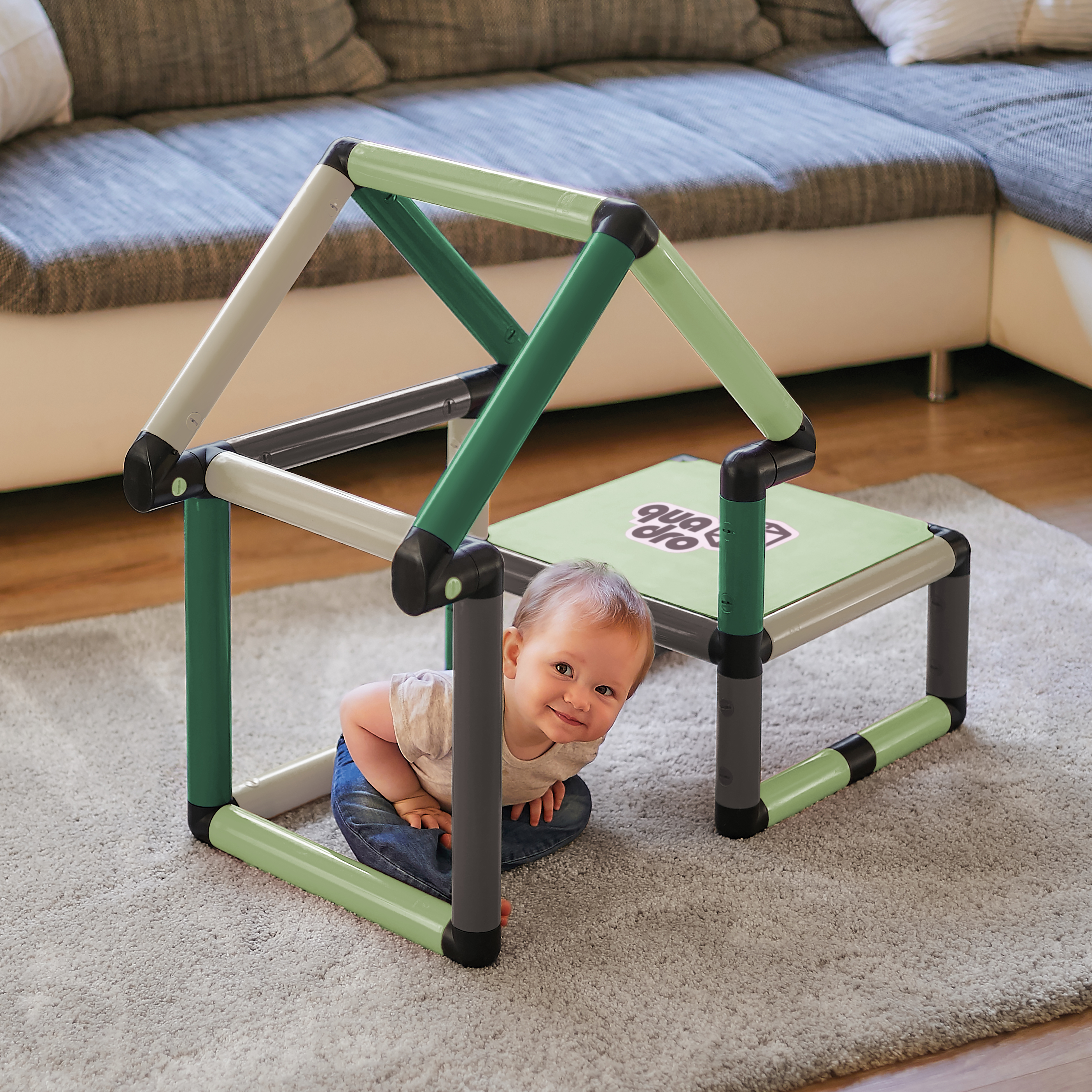 Child sitting inside a playhouse and climbing frame